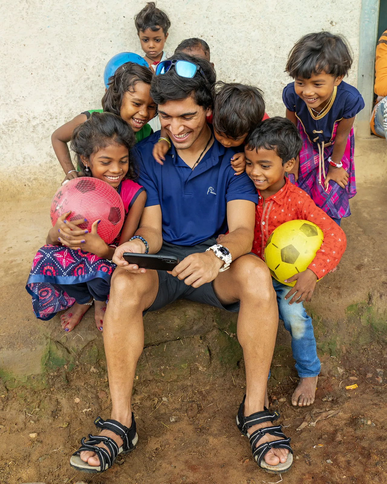 Suyash Keshari sitting with a group of laughing village children