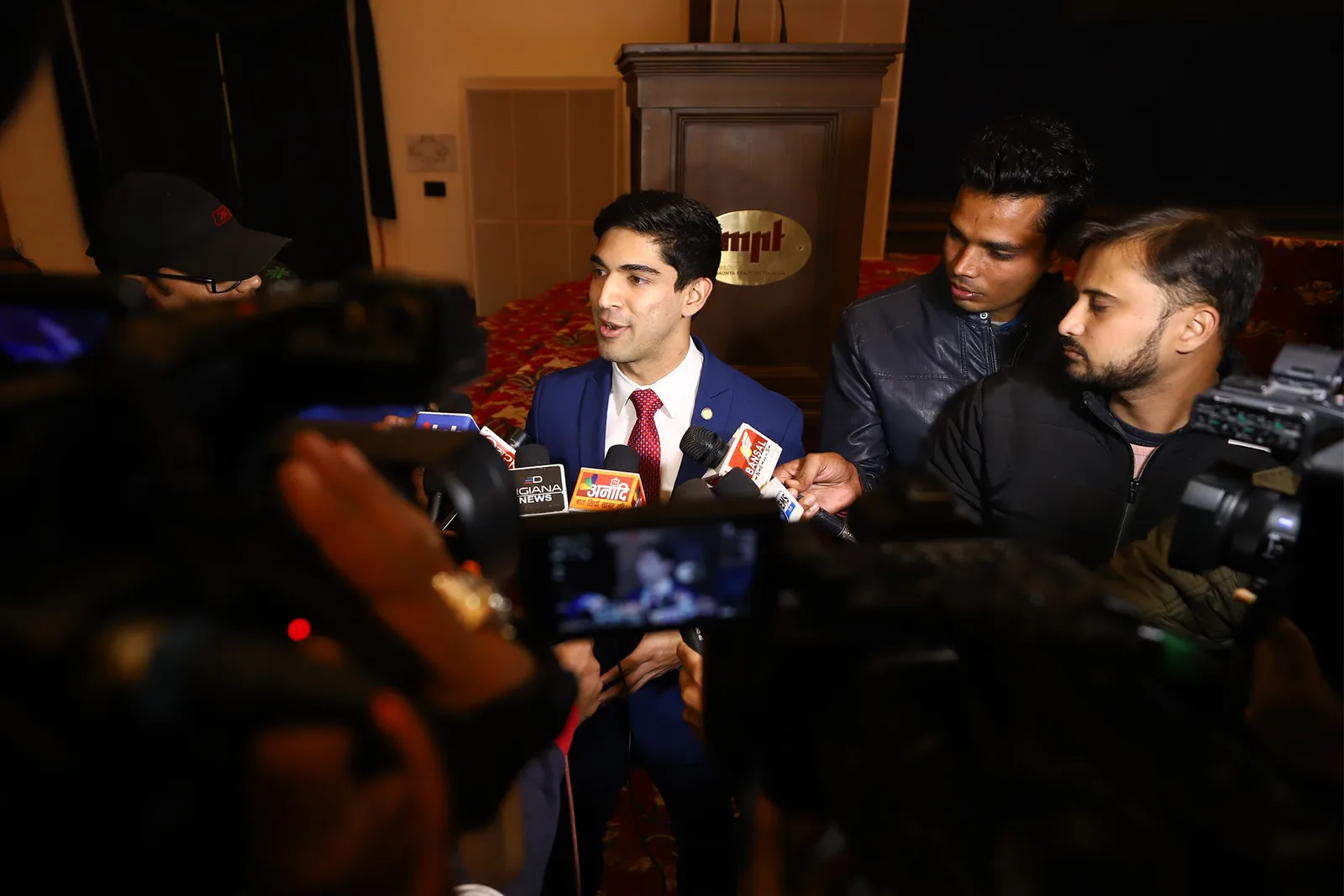 Suyash Keshari speaking to a crowd of press cameras and microphones