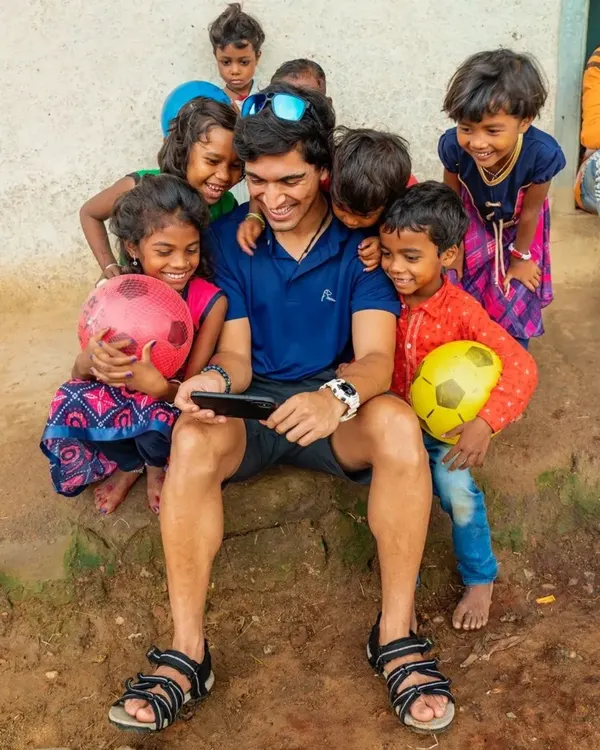 Suyash Keshari sitting with a group of laughing village children